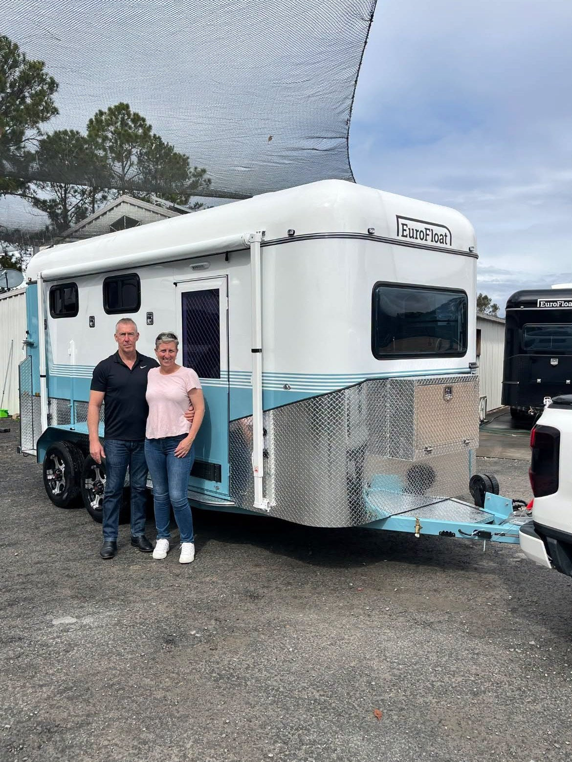 Couple standing beside their new white and teal EuroFloat float