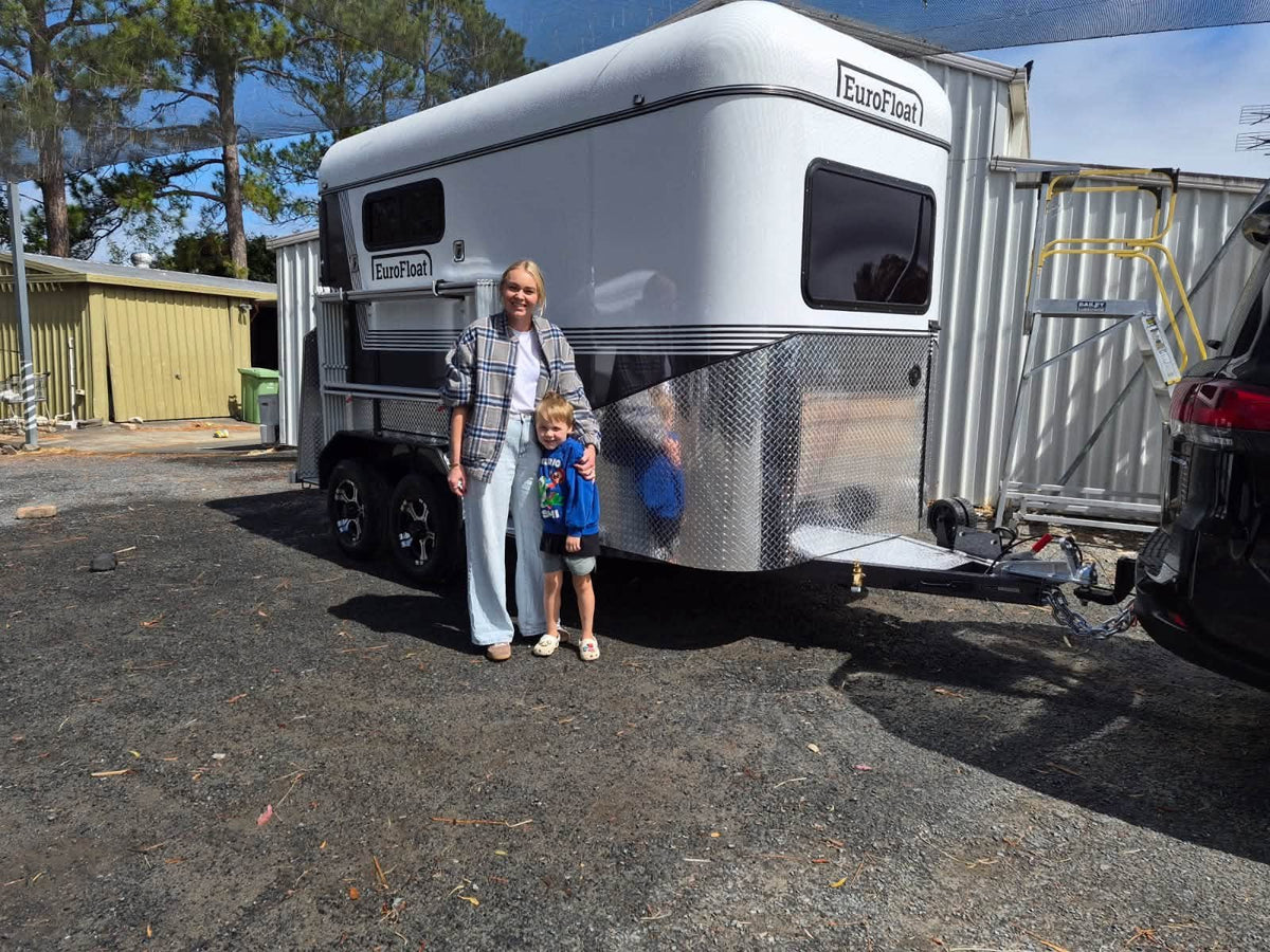 Mum and young son standing beside their new white EuroFloat horse float, hitched and ready to go