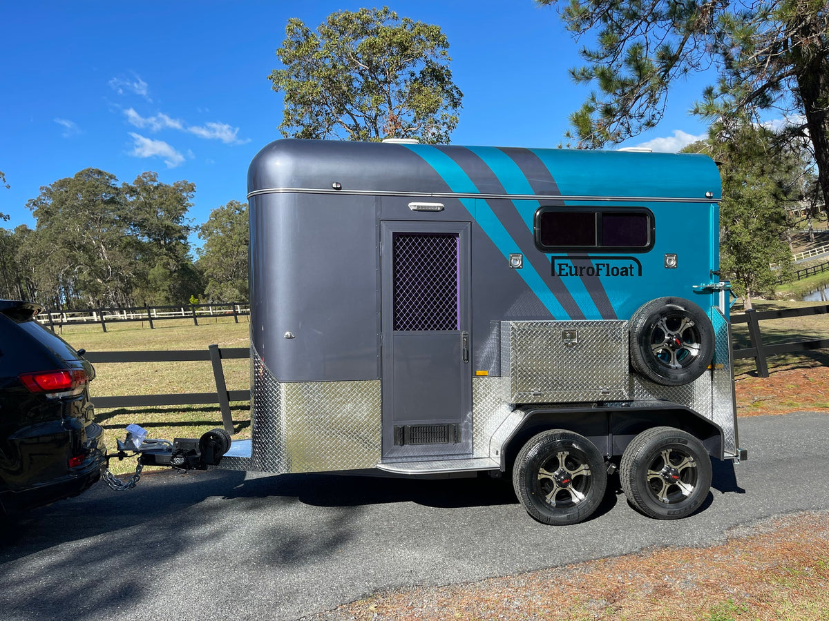Grey and teal EuroFloat float hitched to a black SUV on a country driveway