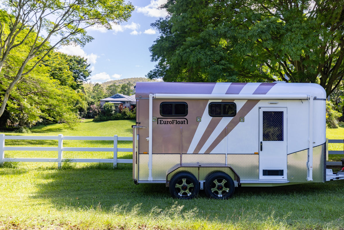 Rose and white EuroFloat float parked beside a white fence in a green paddock