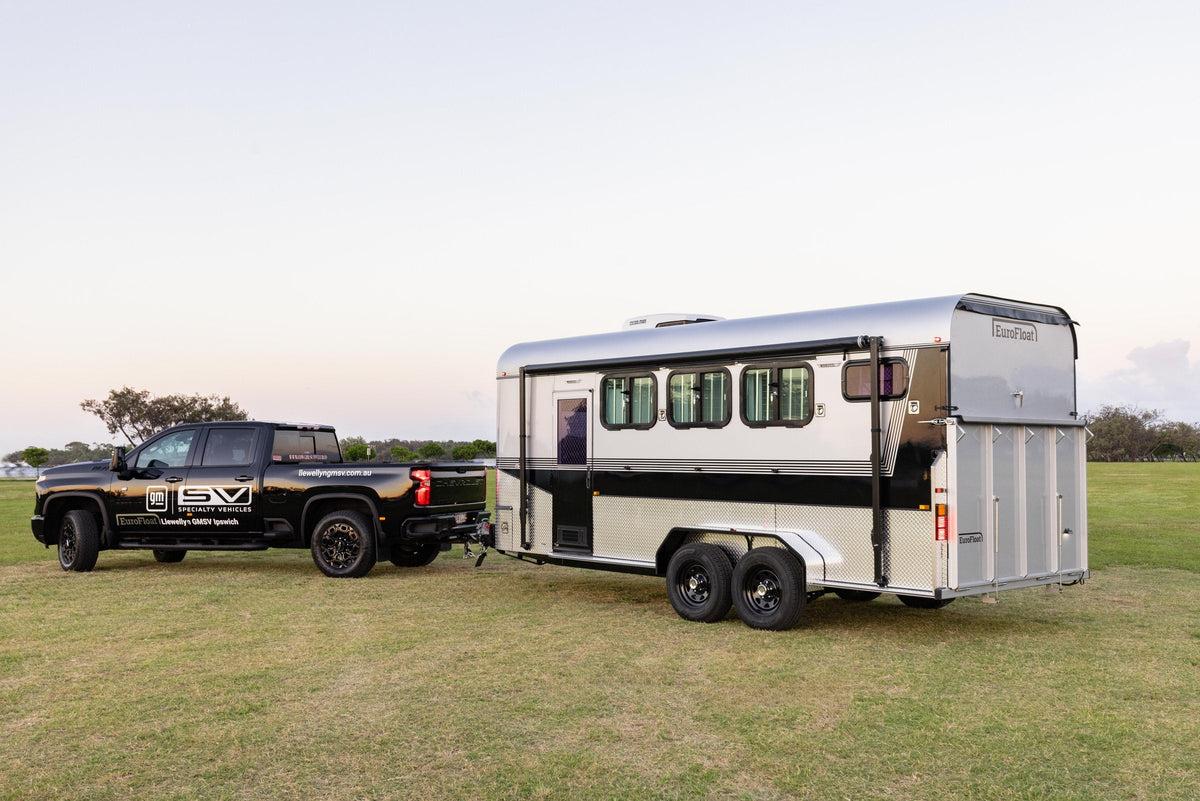 Silver and black EuroFloat horse float hitched to a black ute on open grass at dusk