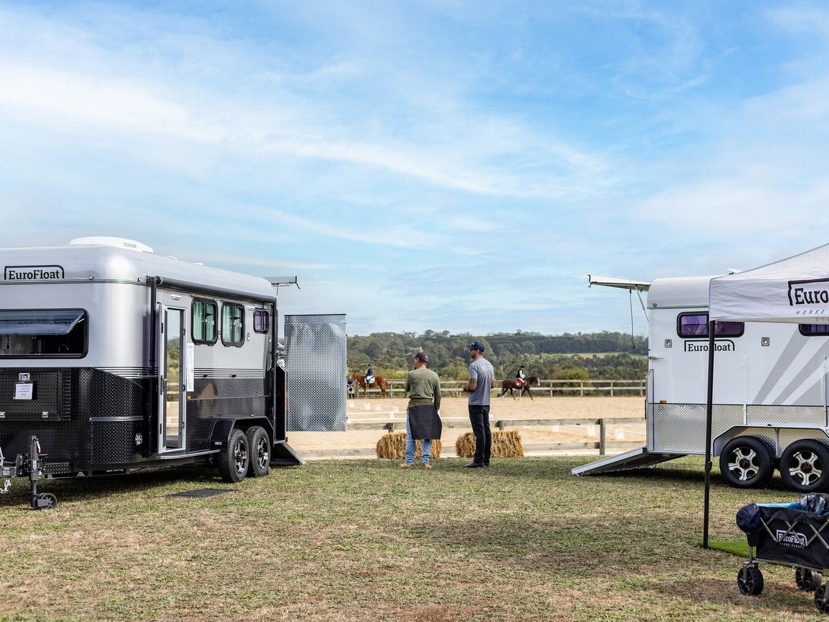 Two EuroFloat floats and a marquee at a show ground, with riders in the arena behind