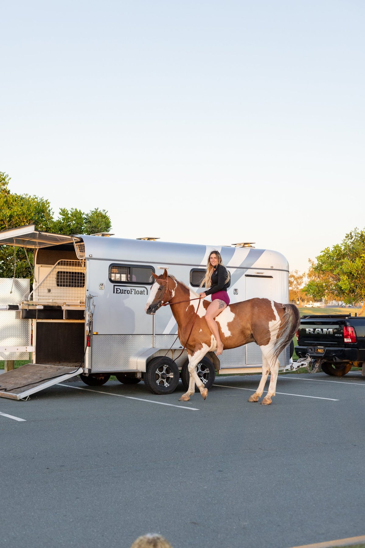 Rider on a paint horse beside an open EuroFloat at golden hour